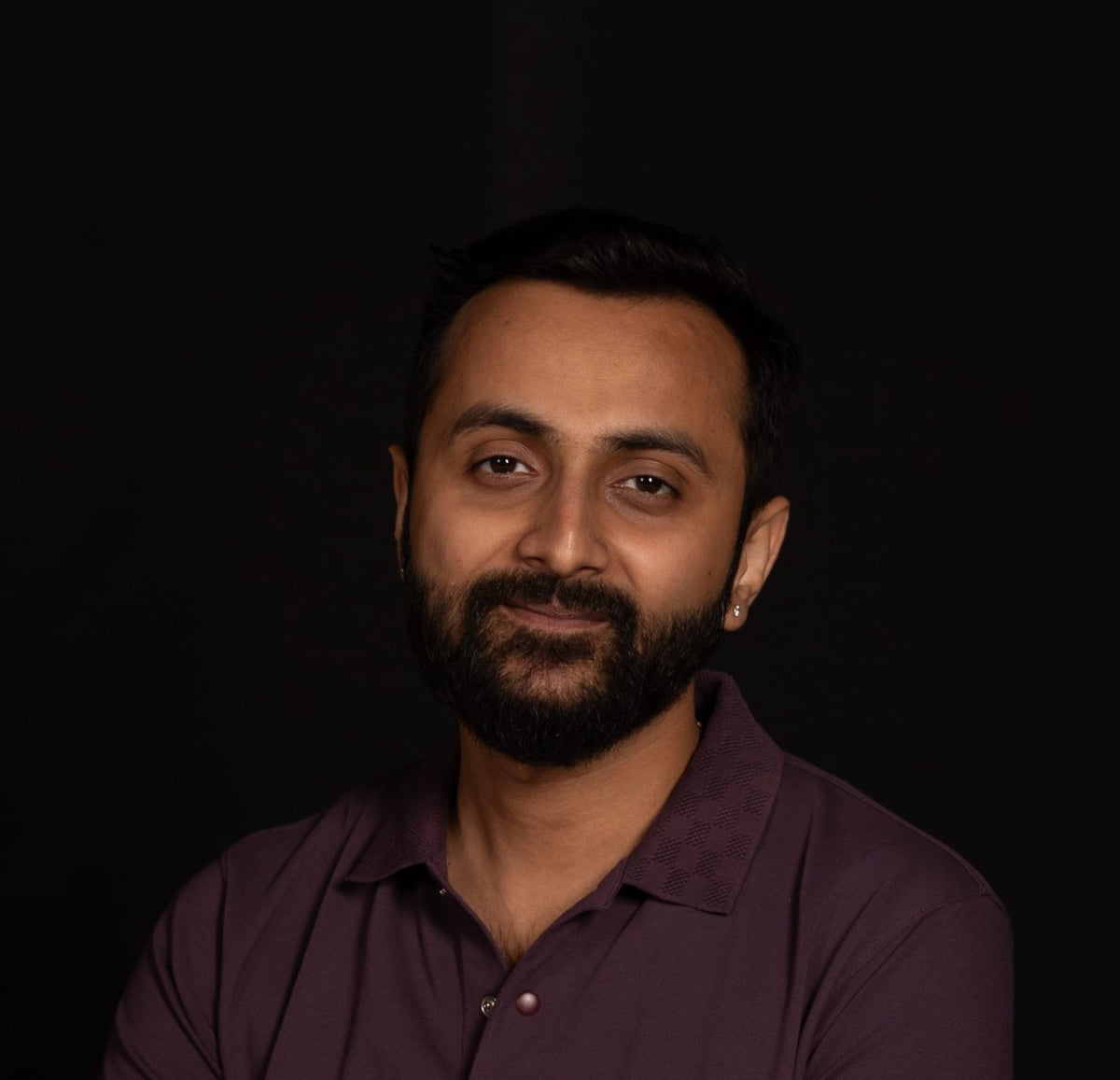 Man wearing a purple shirt against a black background