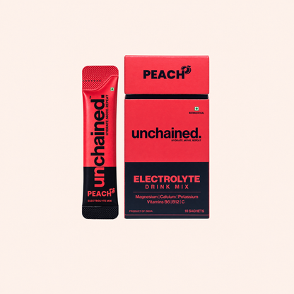 Unchained Peach electrolyte drink mix stick next to its 10-stick box on a peach pink background