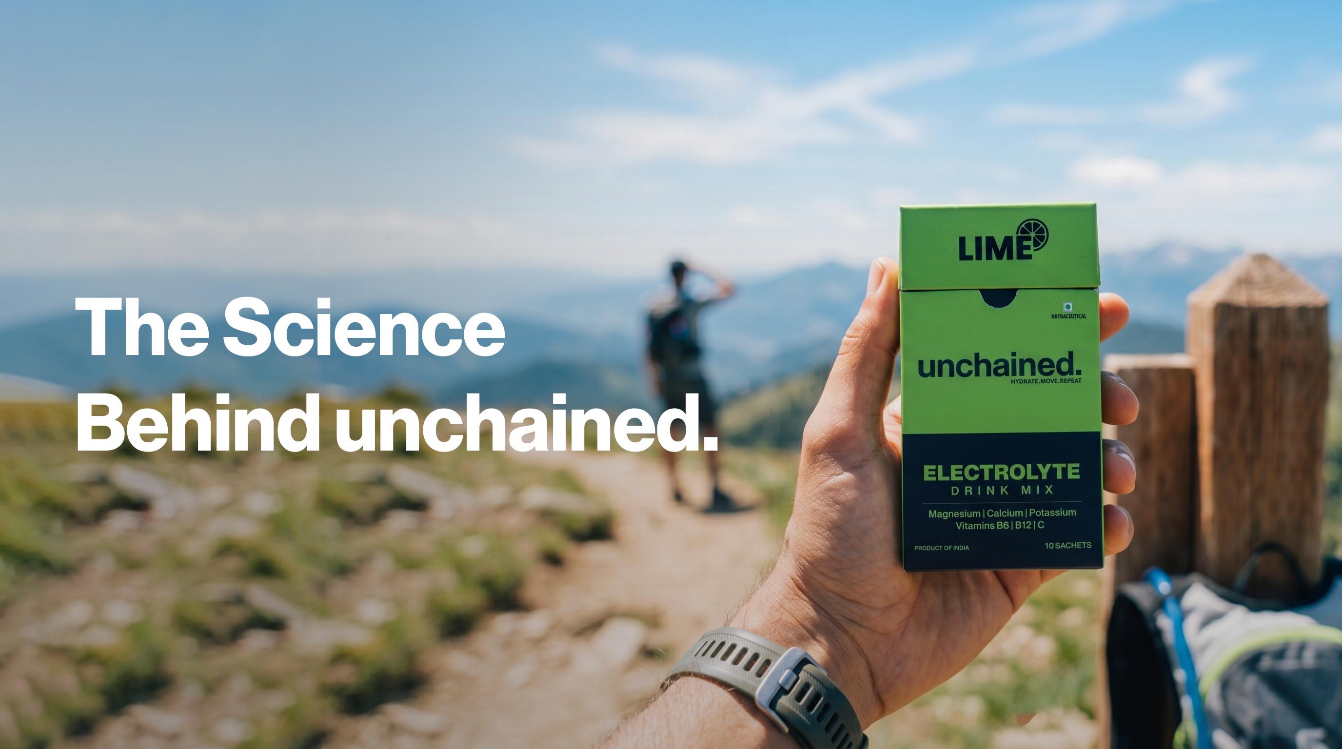 Hand holding a box of 'unchained' electrolyte drink mix with scenic background